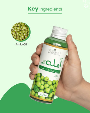 Hand holding Sukoon Amla Oil bottle with fresh amla fruits, highlighting natural hair care ingredient